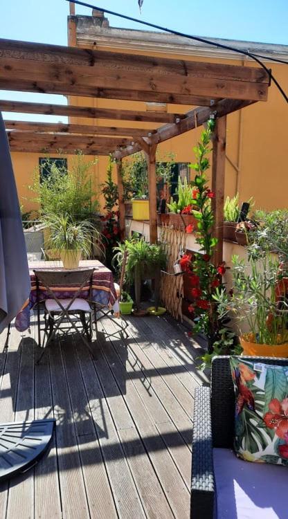 a wooden deck with a table and a pergola at Villa la clémente in Menton