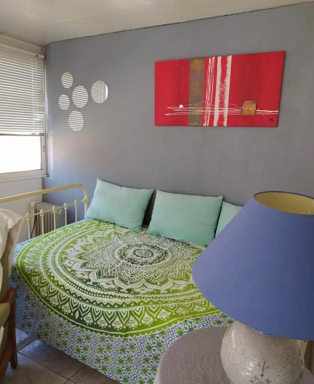 - une chambre dotée d'un lit avec une couverture verte et blanche dans l'établissement Les Goelands ça nous va Appartement entier, à Port-la-Nouvelle