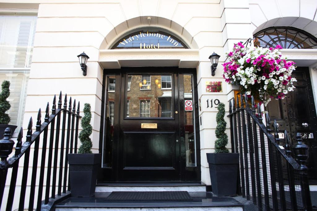 une porte d'entrée noire d'un bâtiment fleuri dans l'établissement Marylebone Inn, à Londres