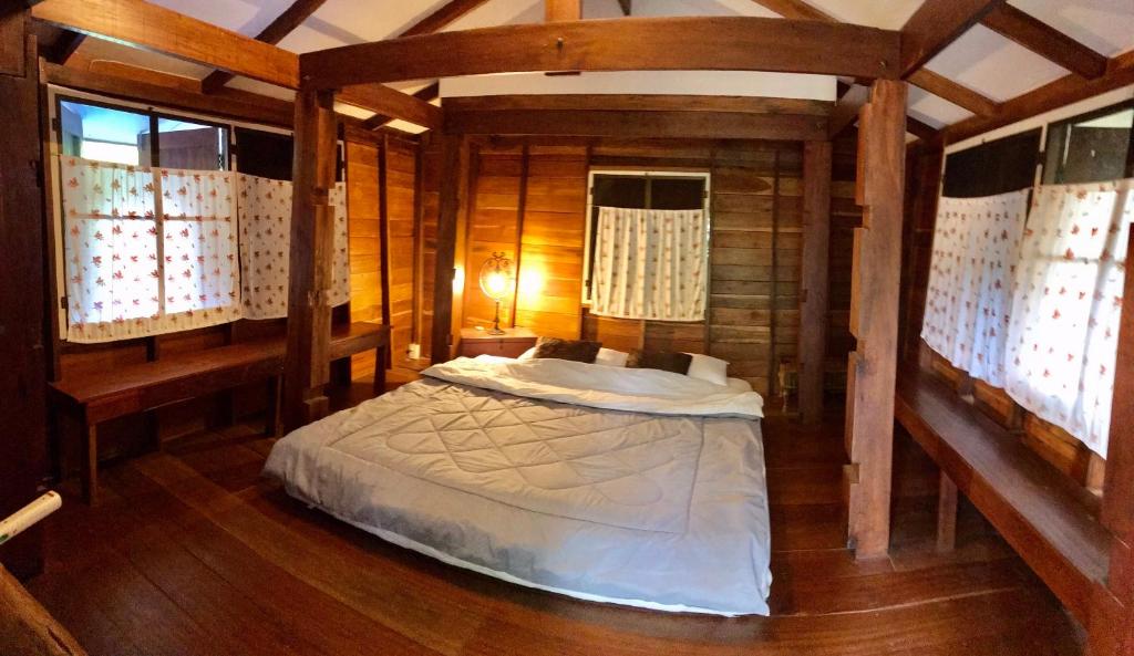 a bedroom with a bed in a room with wooden walls at สวนตุ๊ข้าว(SuanThuKhaw) in Ban Mae Cho