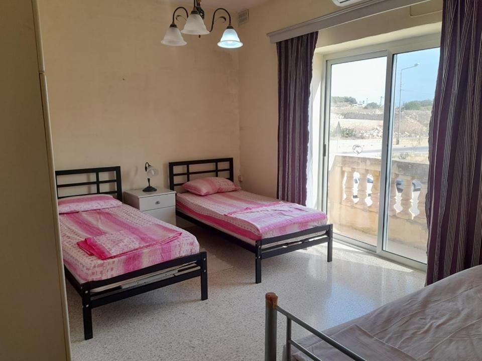 a bedroom with two beds and a window with a view at Dynesty B&B in Birżebbuġa