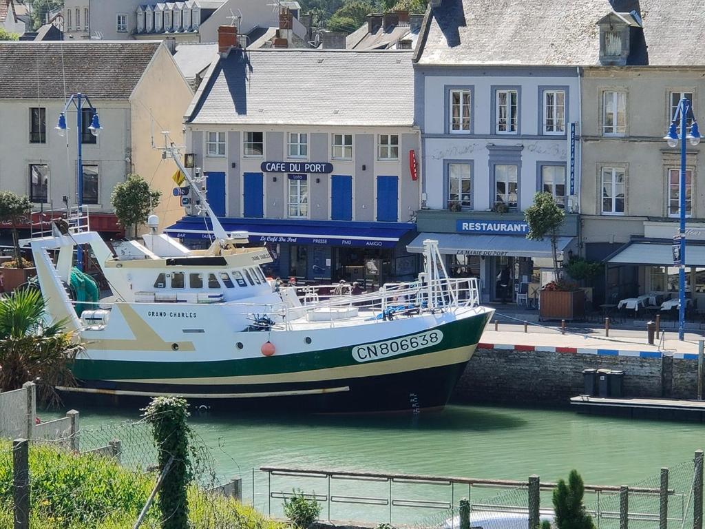 um barco ancorado na água em frente aos edifícios em Fishermen's Friend em Port-en-Bessin-Huppain