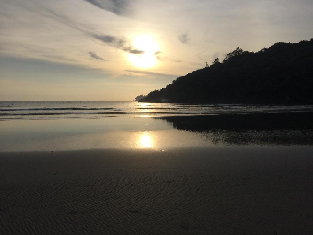 a sunset on a beach with the ocean at Suites Praia de Pernambuco in Guarujá
