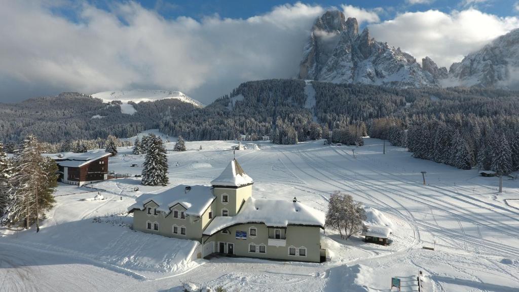 a building in the snow with a mountain in the background at Villa Pana in Santa Cristina Gherdëina