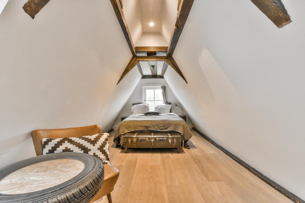 een slaapkamer op zolder met een bed en een stoel bij Herengracht Private room with canal view in Amsterdam