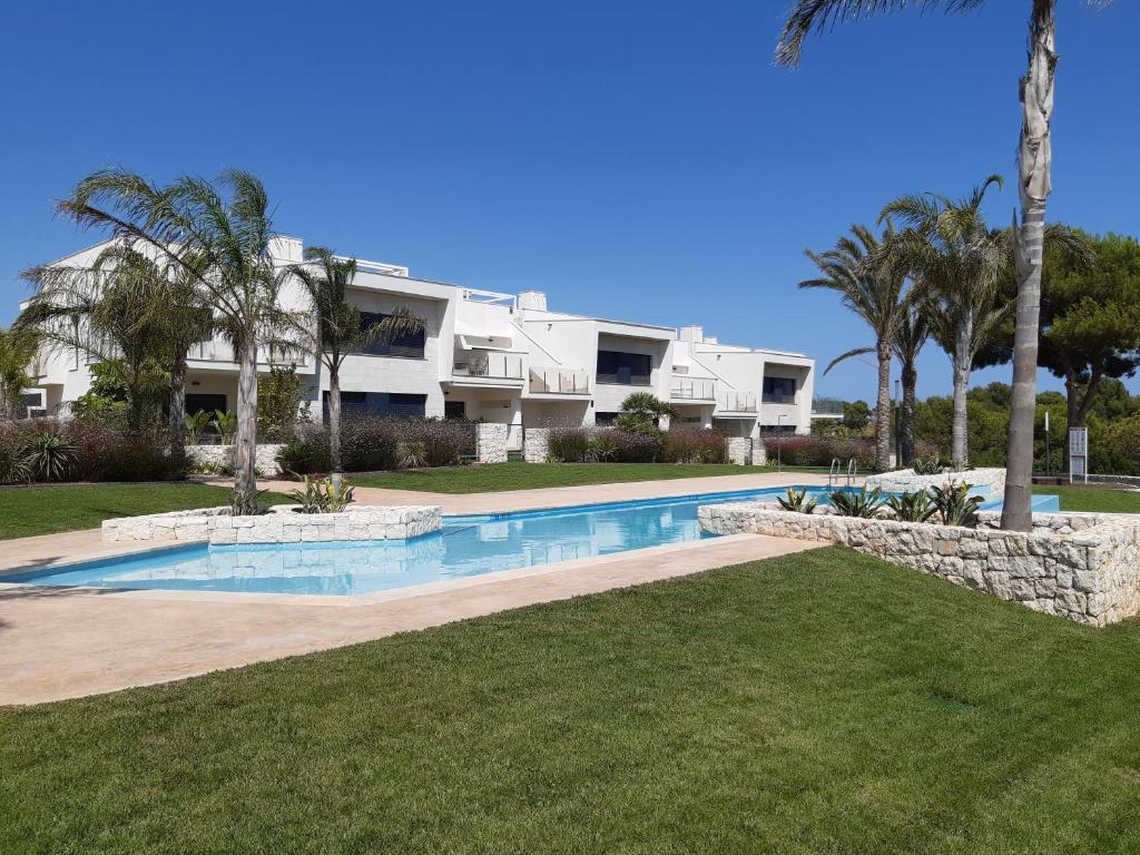 a villa with a swimming pool and palm trees at Prachtig penthouse appartement op Lo Romero golf in Pilar de la Horadada