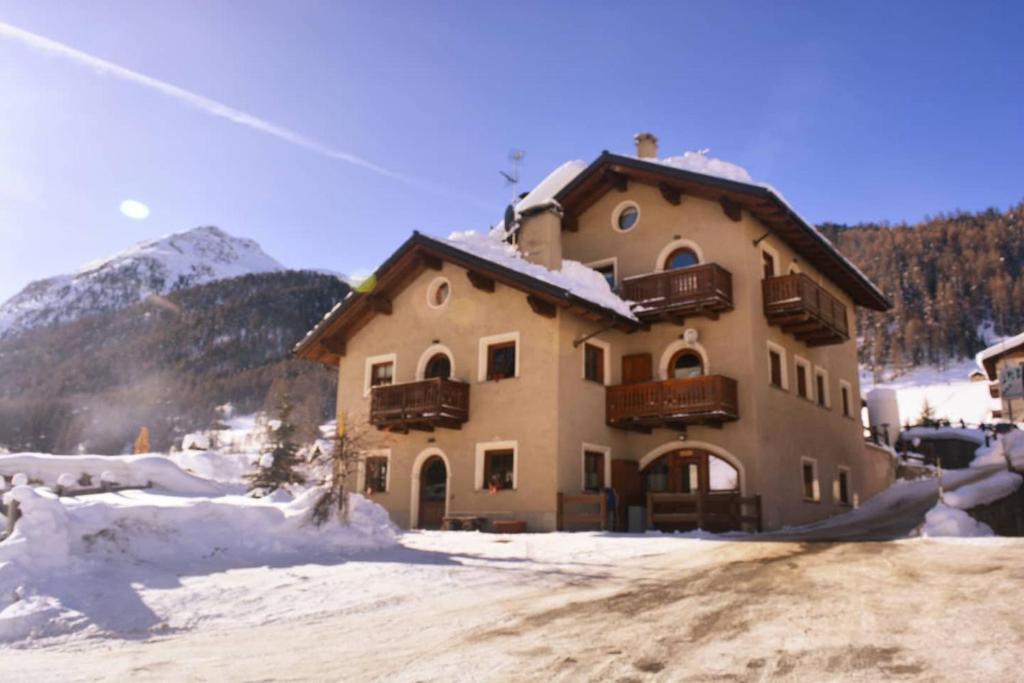 een groot gebouw met sneeuw op de grond voor de deur bij Snowflake Apartment in Livigno