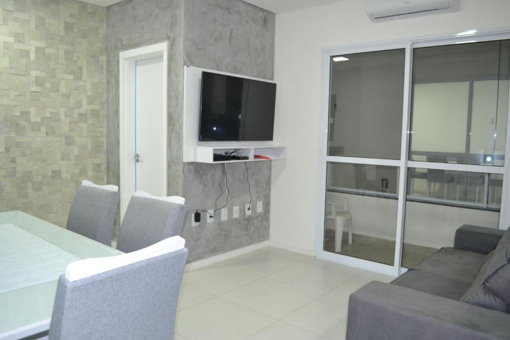salon ze stołem, krzesłami i telewizorem w obiekcie Apartamento Praia do Santinho w mieście Florianópolis