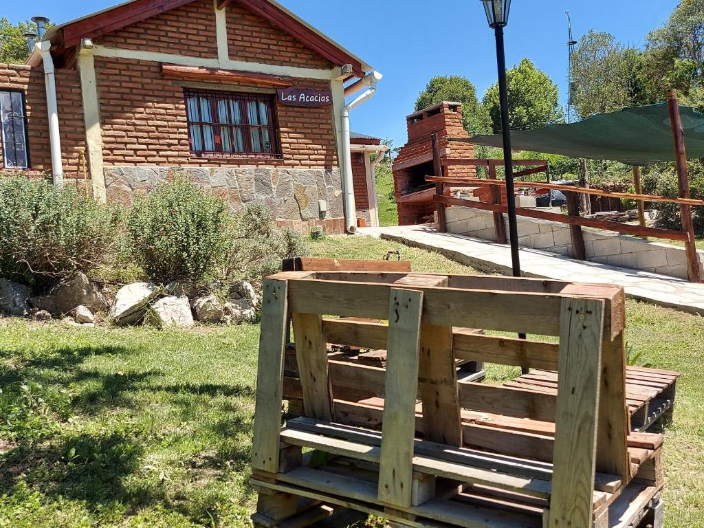 un banco de madera sentado en el césped frente a una casa en Terra Vista en Huerta Grande