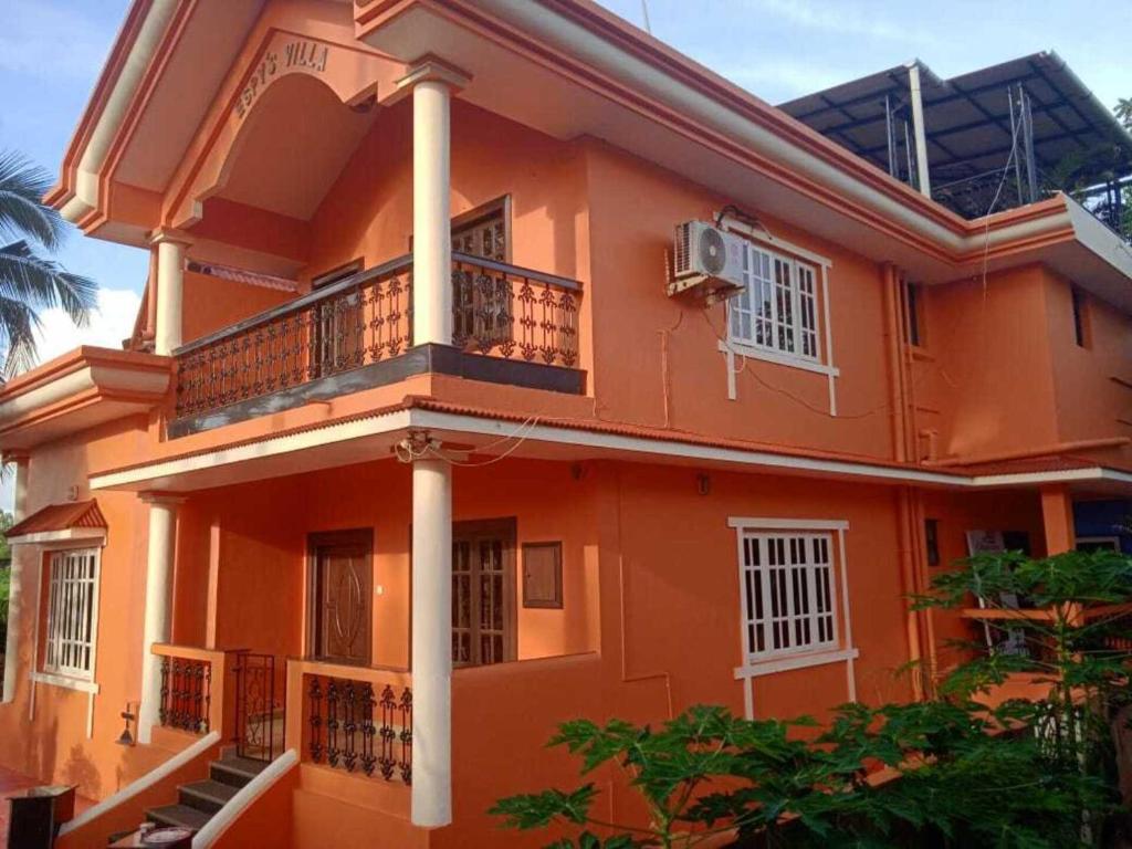 ein großes Orangenhaus mit einem Balkon und Bäumen in der Unterkunft Stunning luxury Villa in Goa India in Colva