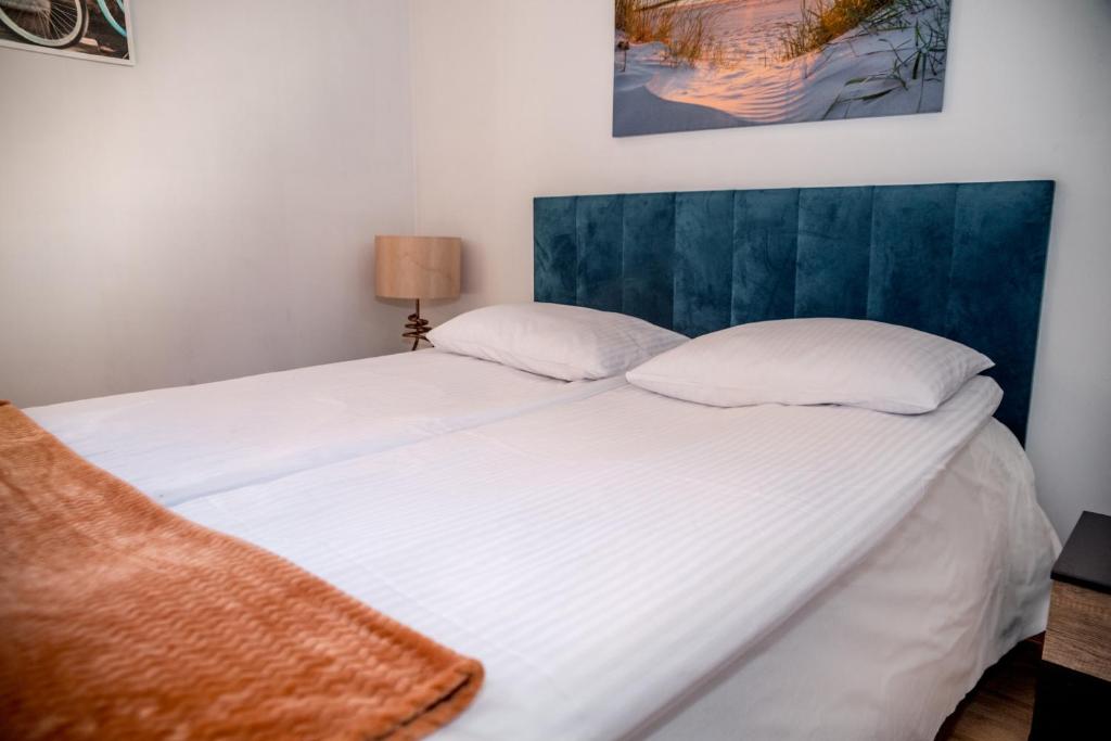 a bed with white sheets and a blue headboard at Domjana Lubiatowo in Lubiatowo