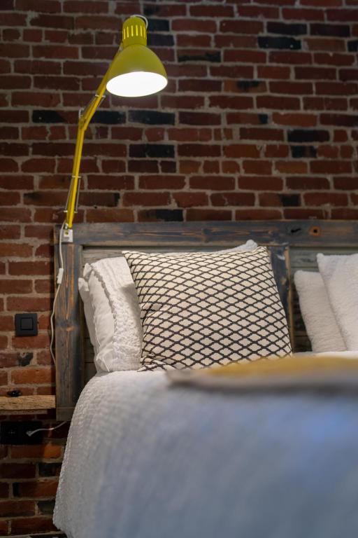 a bed with a lamp next to a brick wall at Vakantiehuis ABEL in Dilsen-Stokkem