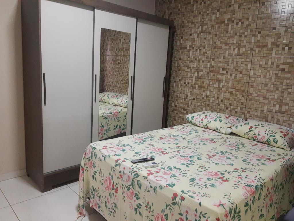 a bedroom with a bed with a floral bedspread and a closet at Ilhéus apto 01 exclusivo in Ilhéus
