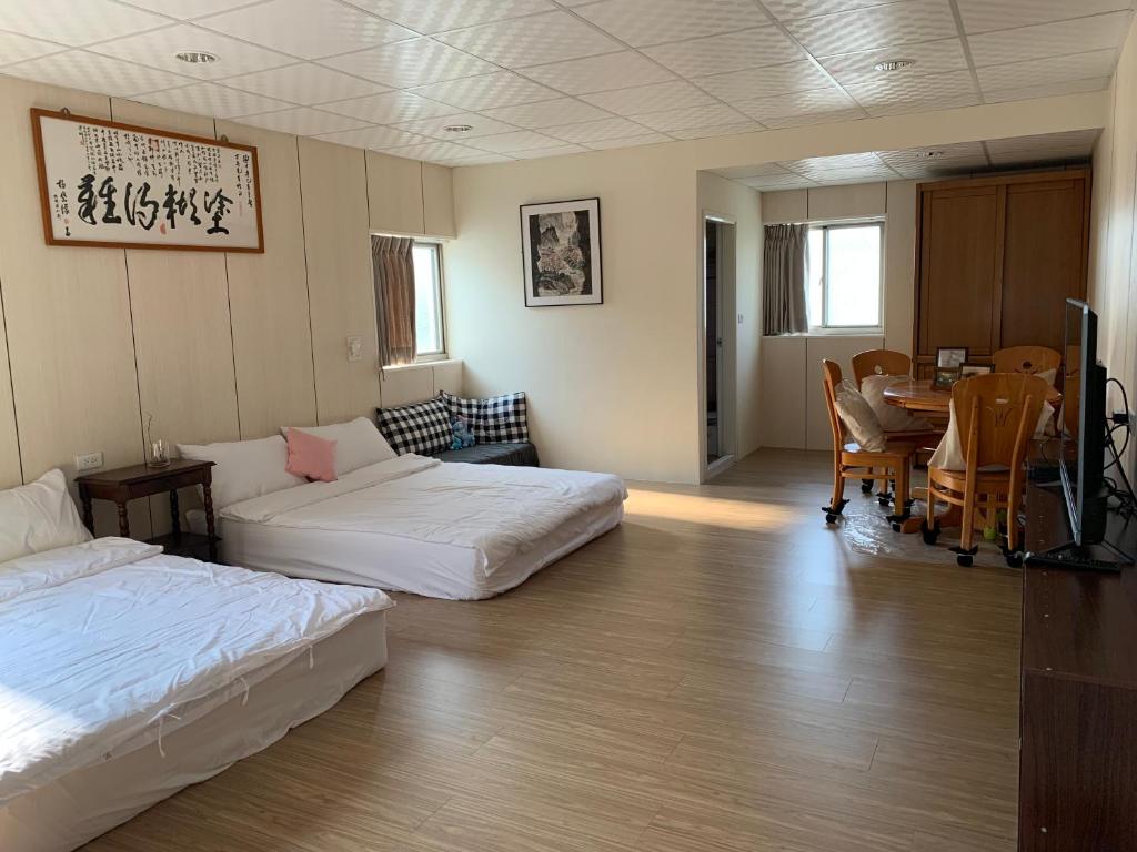 a room with two beds and a table and a dining room at Guan Ma Homestay in Miaoli