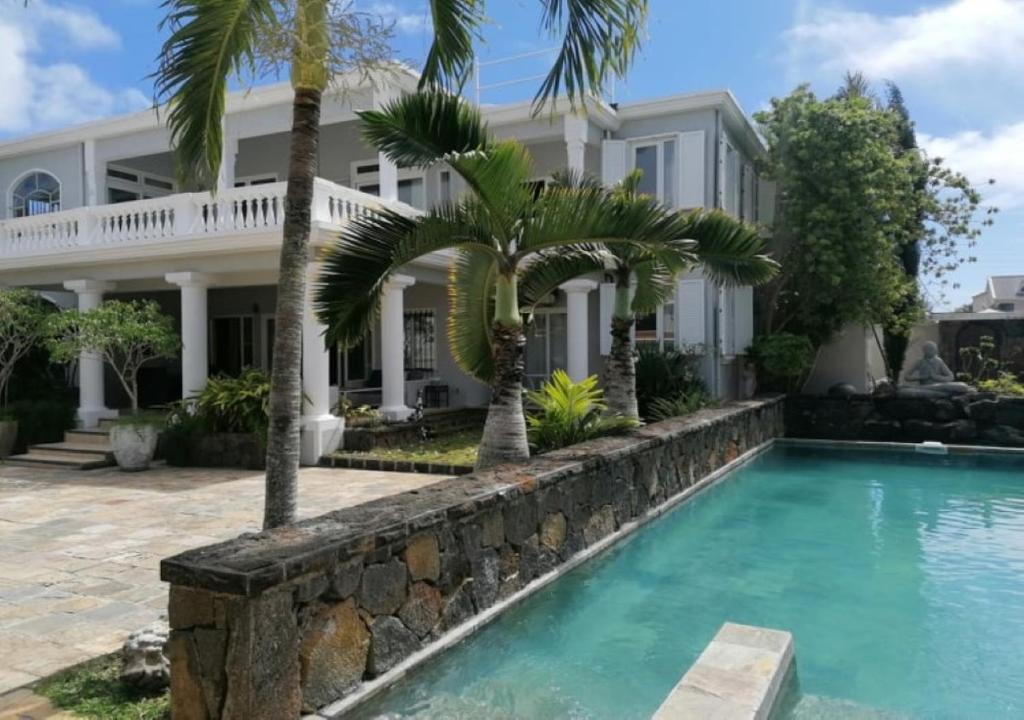 a house with a swimming pool and palm trees at Luxury Villa L'ile Maurice in Pointe aux Cannoniers