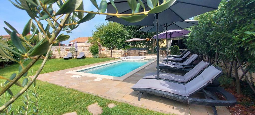 un gruppo di sedie e un ombrellone accanto alla piscina di Rooms and Apartments IstraSoley a Bale (Valle)