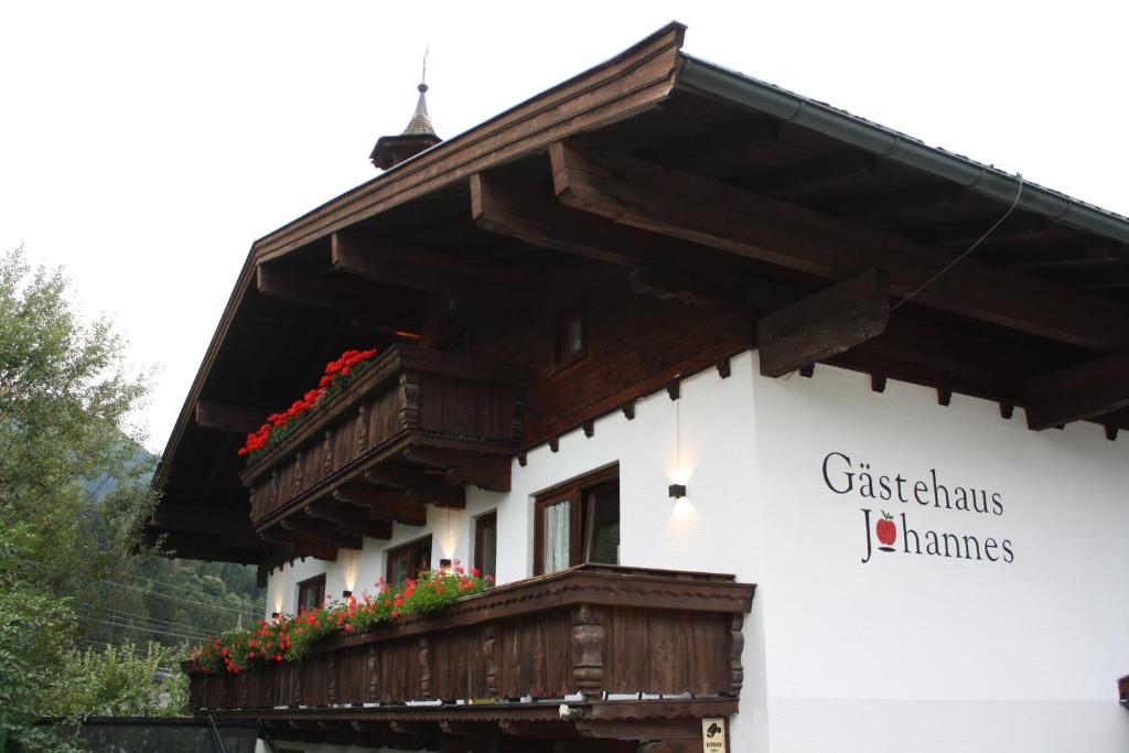a building with a balcony with flowers on it at Gästehaus Johannes in Niedernsill