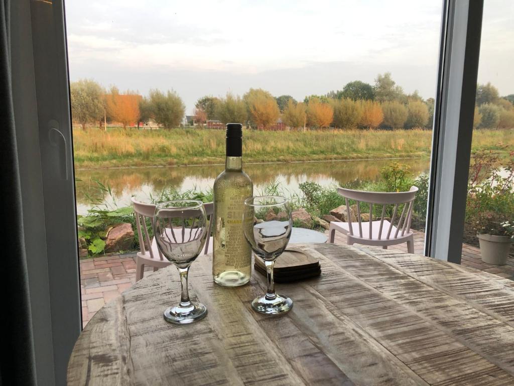 una bottiglia di vino seduta su un tavolo con due bicchieri da vino di B&B Stien, fijn verblijf aan open vaarwater a Stiens