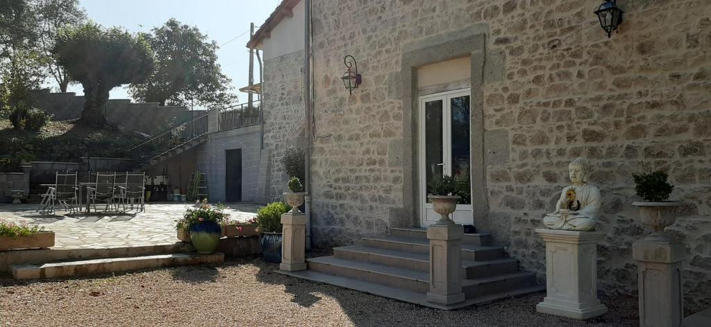 a stone house with stairs and a statue on it at Le Domaine de la plume in La Gimond