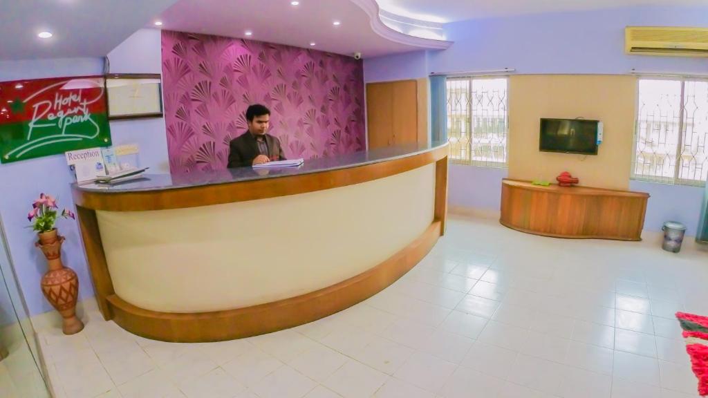 a man sitting at a counter in a room at HOTEL REGENT PARK in Chittagong