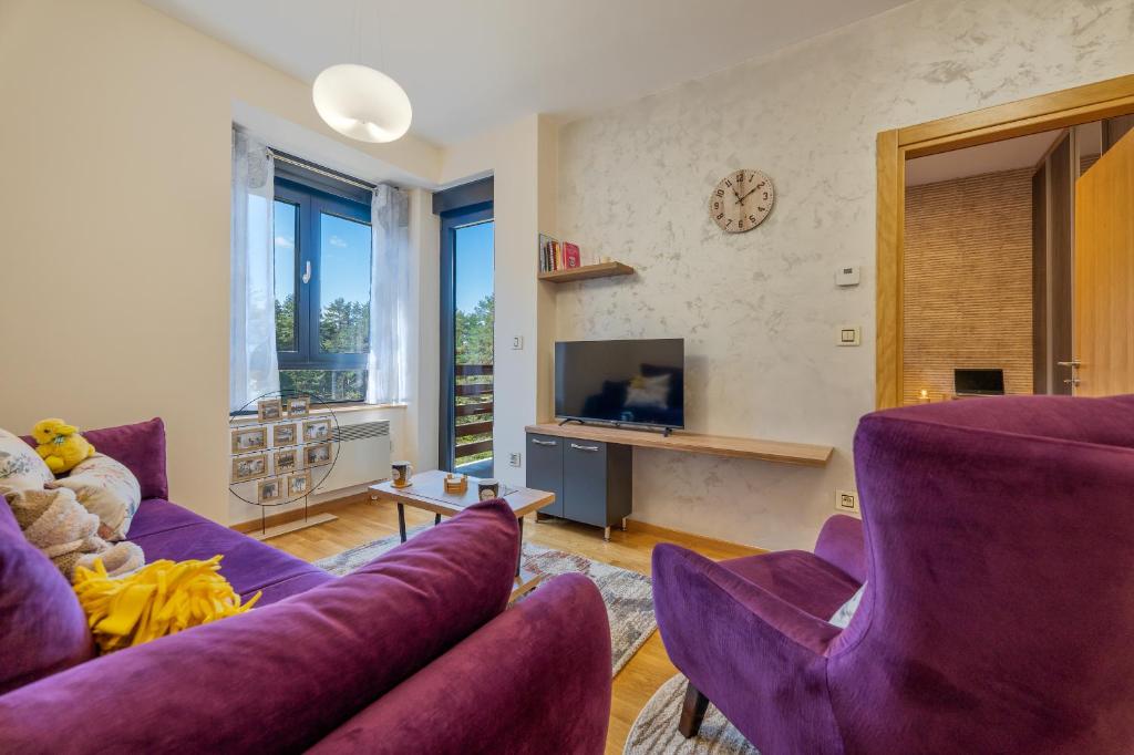 Apartman Enjoy في زلاتيبور: غرفة معيشة مع أرائك أرجوانية وتلفزيون