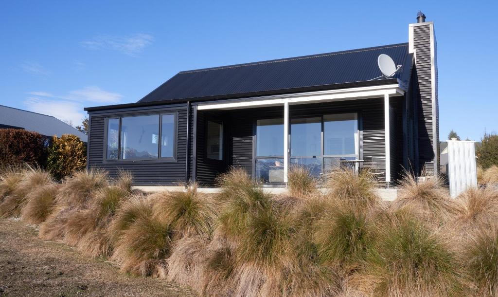 a black house with large windows and some grass at Cass Crib - Lake Tekapo in Lake Tekapo