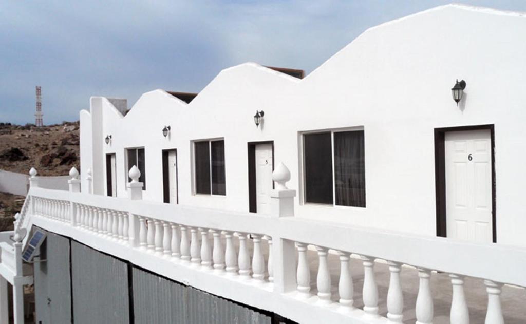 a white house with black windows and a fence at Whale Hill in Puerto Peñasco