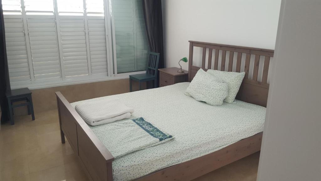 Schlafzimmer mit einem Bett mit weißer Bettwäsche und Kissen in der Unterkunft Room near Sheba Medical Center, and Bar Ilan, and TLV Airport in Qiryat Ono