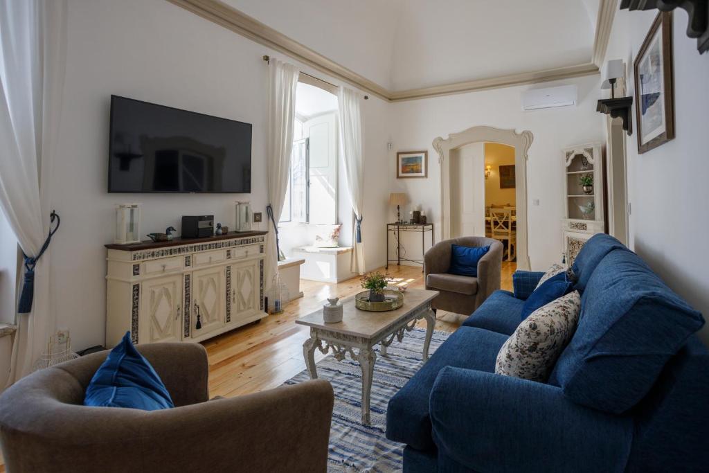 a living room with blue couches and a tv at Casa do Povo in Elvas