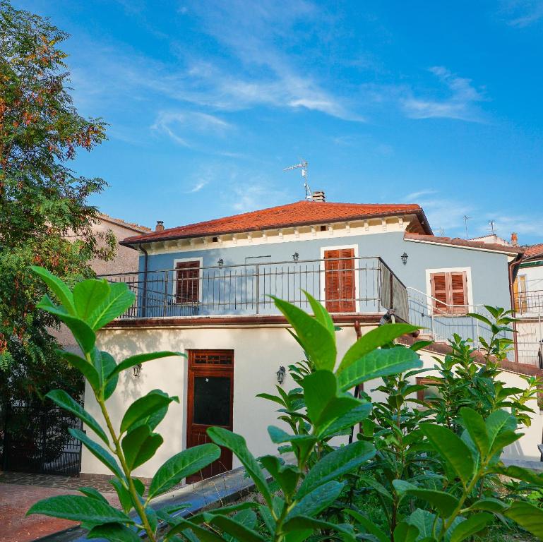 uma casa branca com varanda e árvores em La Terrazza Azzurra em Bellisio di Sopra