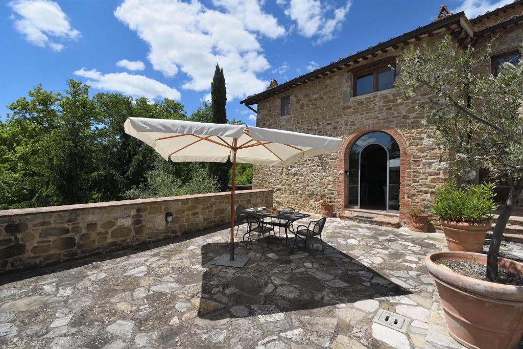 a patio with a table and an umbrella at Vin Santo in Castelnuovo Berardenga