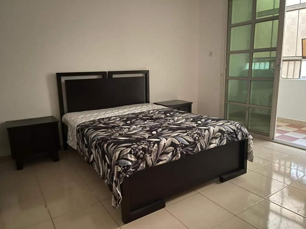 a bedroom with a bed with a black and white comforter at Furnished hone stay villa with attached bathroom with balcony in Al 'Ayn