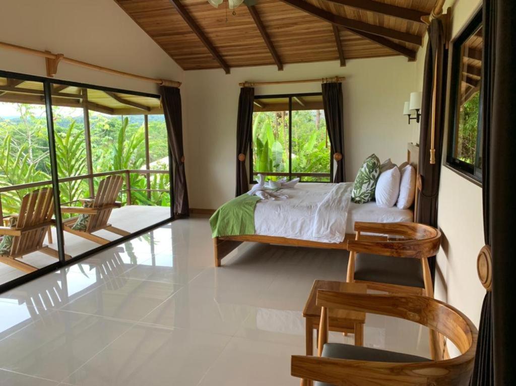 a bedroom with a bed and some chairs and windows at Drake Bay Greenleaf in Drake