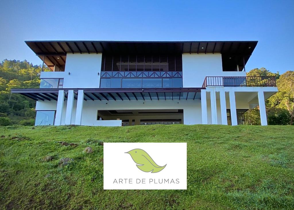 Arte de Plumas birding lodge في كرتاغو: منزل على تلة مع علامة أمامه