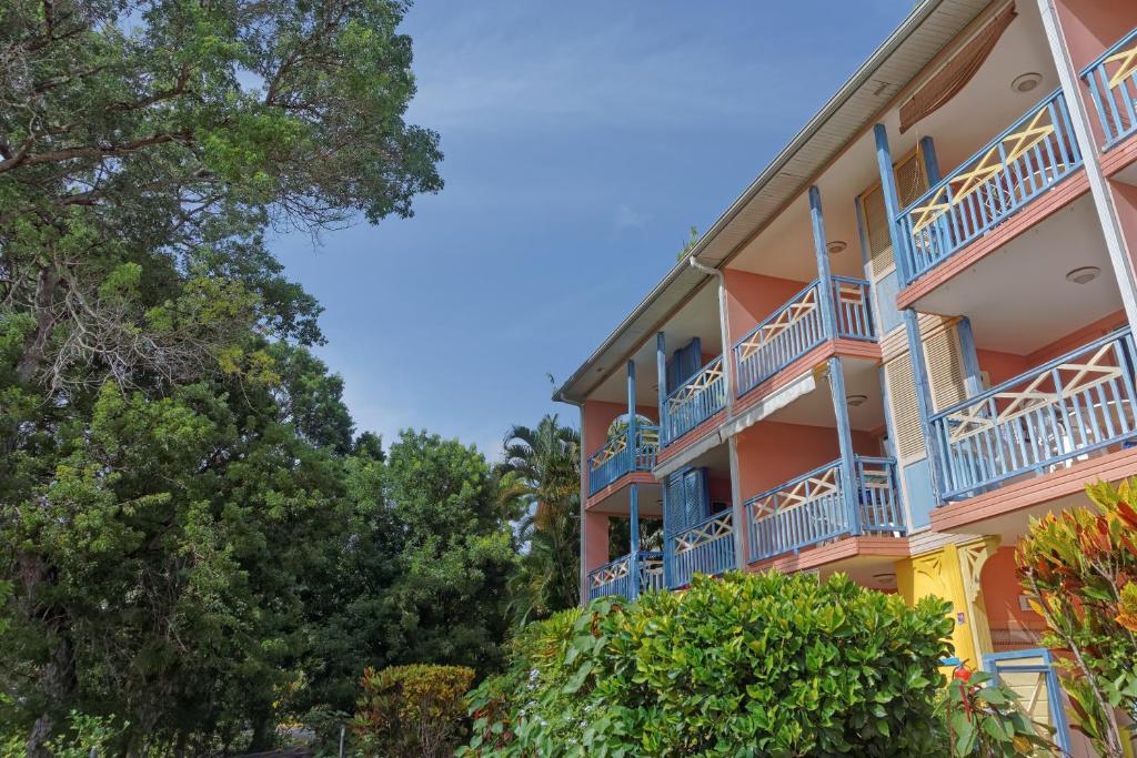 ein orangefarbenes Gebäude mit blauen Balkonen und Bäumen in der Unterkunft Les Studios Kazado in Sainte-Anne