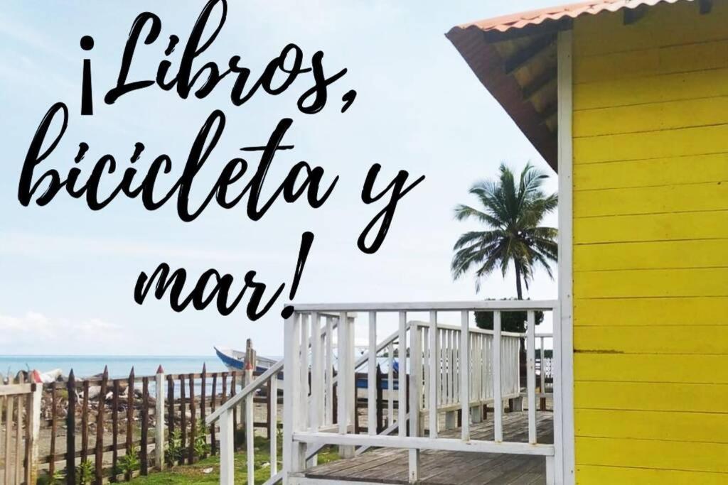 uma casa de praia com um exterior amarelo e branco e as palavras borboleta litzitz em La Casa Amarilla (Sobre las playas del mar Caribe) em San Bernardo del Viento