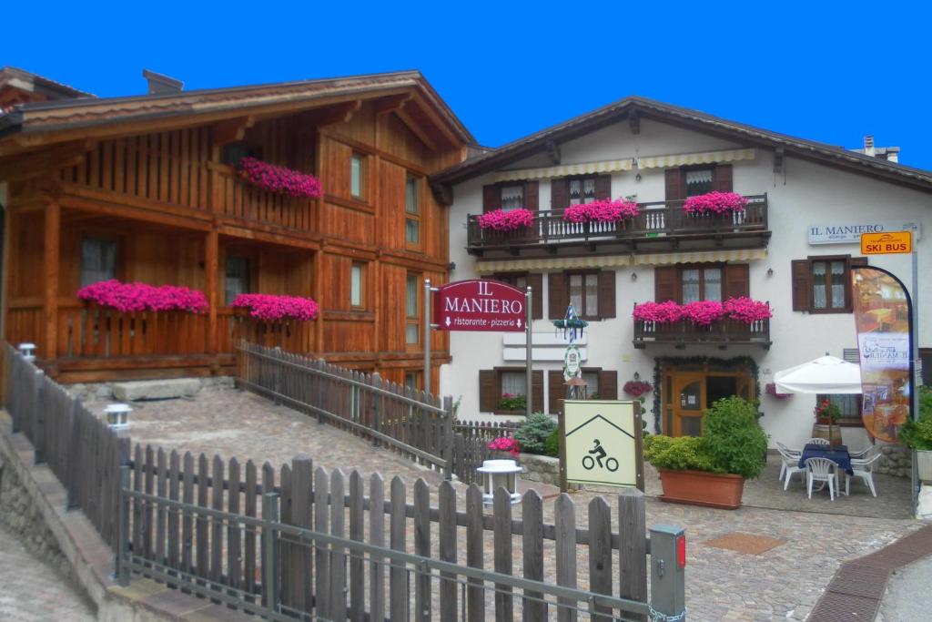 a building with pink flowers on the balconies of it at Hotel Il Maniero in Ossana