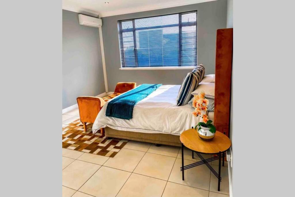 Un dormitorio con una cama y una mesa y una ventana. en Summerstrand Boutique Beach Apartment, en Summerstrand