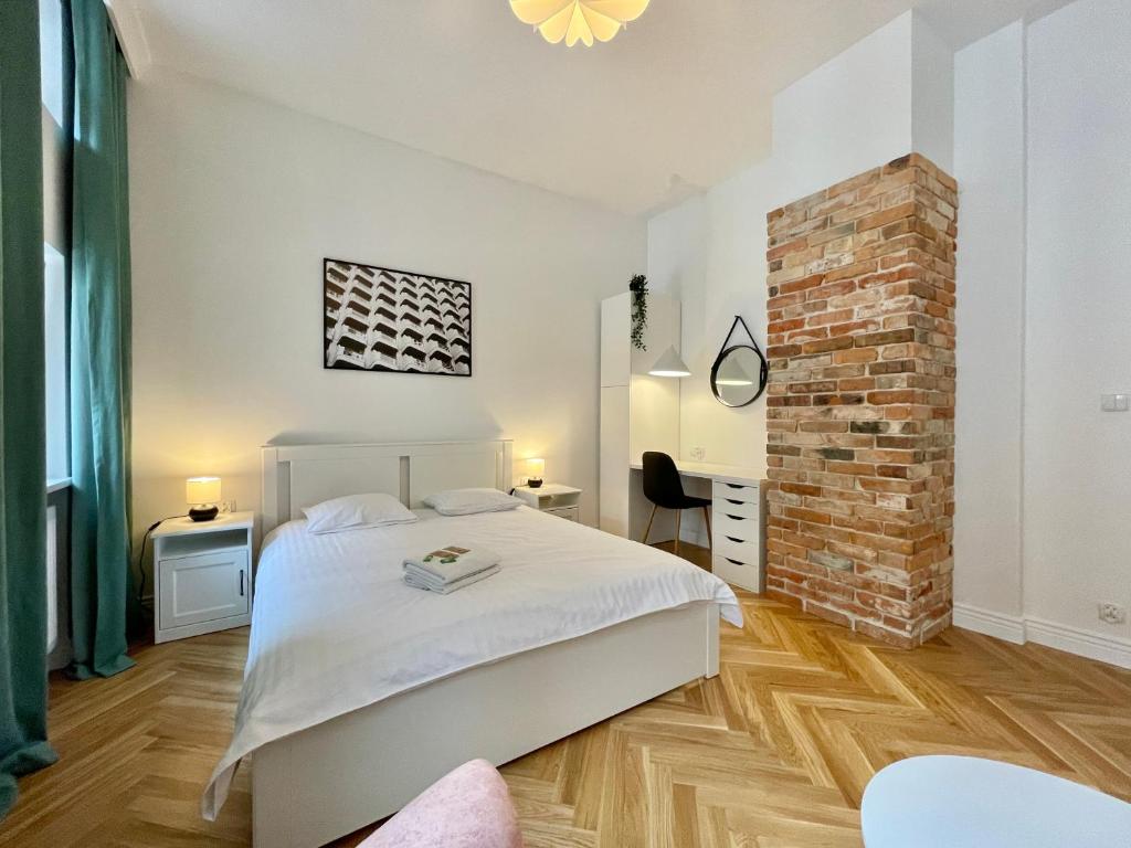 sypialnia z białym łóżkiem i ceglaną ścianą w obiekcie Chili Apartment w Toruniu