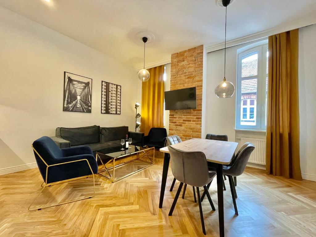 uma sala de estar com uma mesa e um sofá em Chili Apartment em Toruń