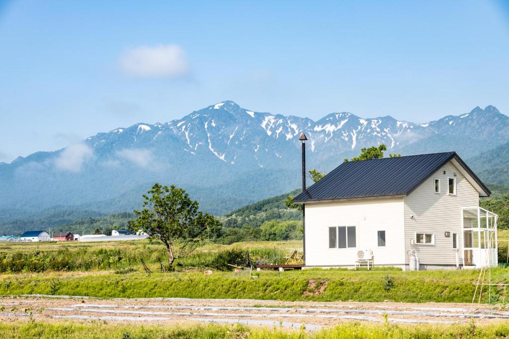 a white house in a field with mountains in the background at agris FURANO 01 FARM GUEST HOUSE in Nunoppe