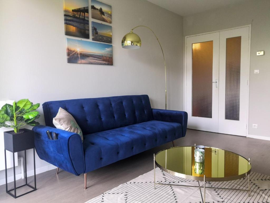 a blue couch in a living room with a glass table at Appartement Toulouse Blagnac MEET Aéroport 5 min Tramway à 6 min free Parking Proche de toutes commodités Belle terrasse in Blagnac
