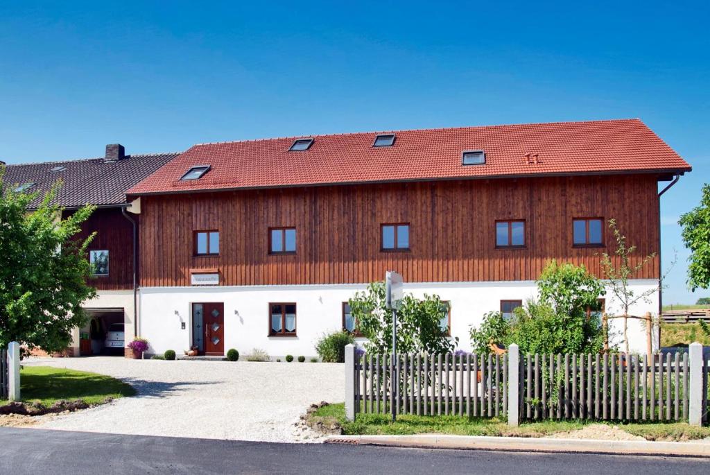 a large red and white building with a fence at Pension Kramerhof in Taufkirchen