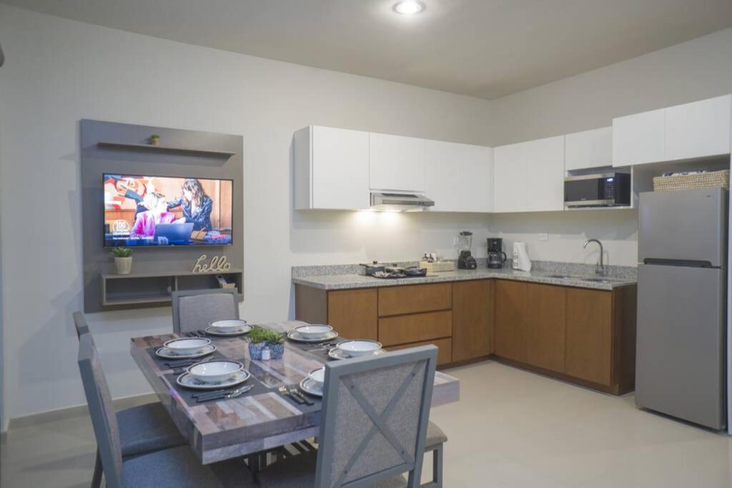 a kitchen with a table with chairs and a television at Departamento Atlántico Alberca y Casa Club in Mazatlán