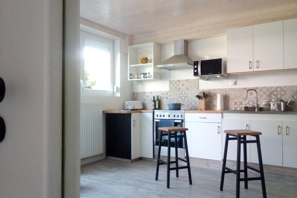 a kitchen with white cabinets and stools in it at T2 Rdc, jardin, calme, parking, idéalement placé in Issoire