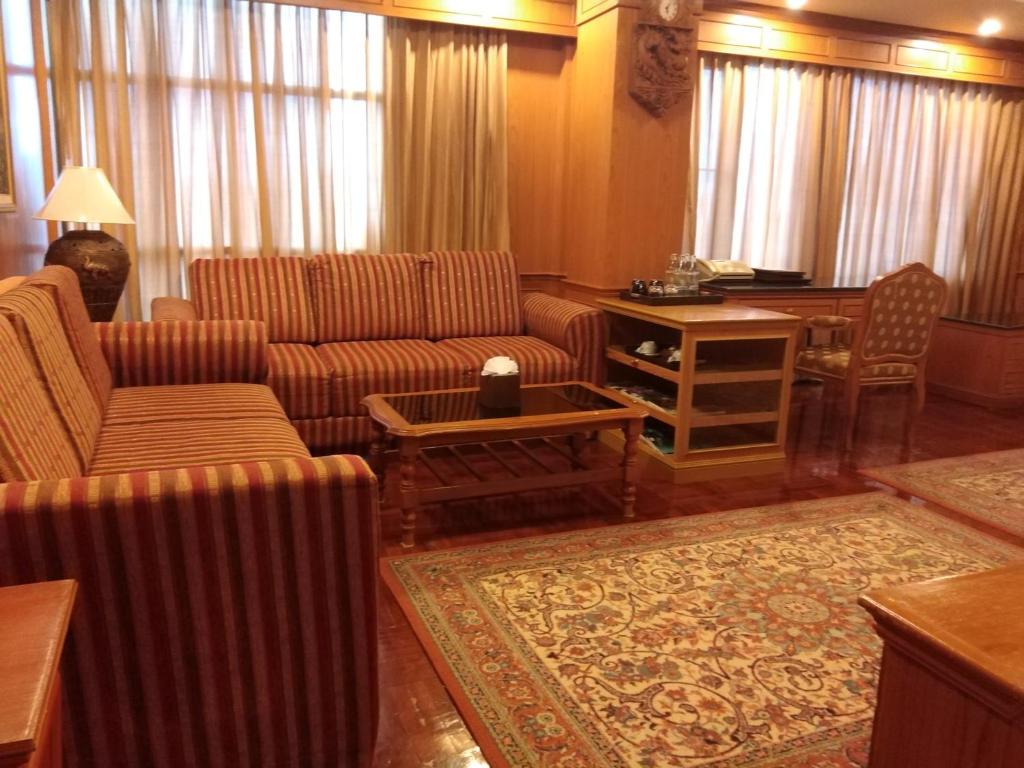 uma sala de estar com sofás, uma mesa e uma secretária em Taksilahotel em Maha Sarakham