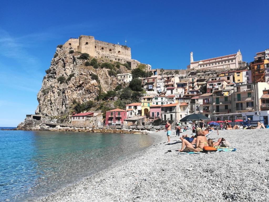 a group of people sitting on a beach with a castle at Appartamenti SPA in Scilla