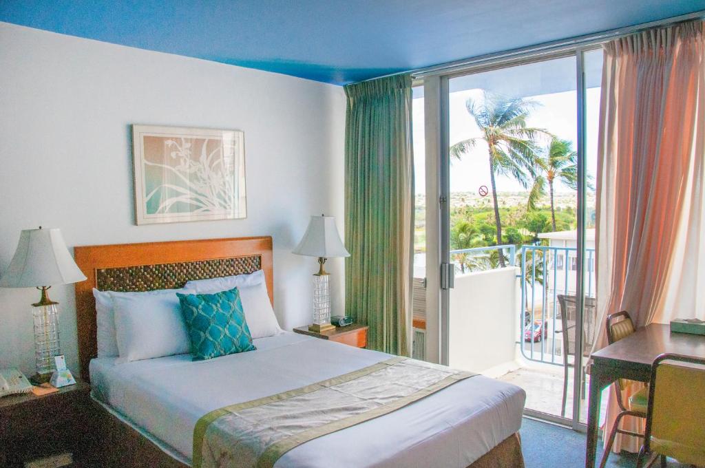 um quarto de hotel com uma cama e uma varanda em Holiday Surf Hotel (with full kitchen) em Honolulu