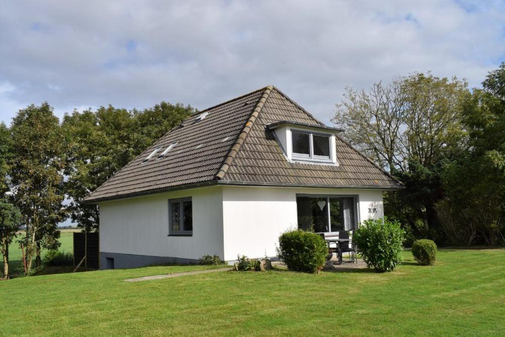 a small white house with a roof on a field at Haus Storjohann in Dagebüll