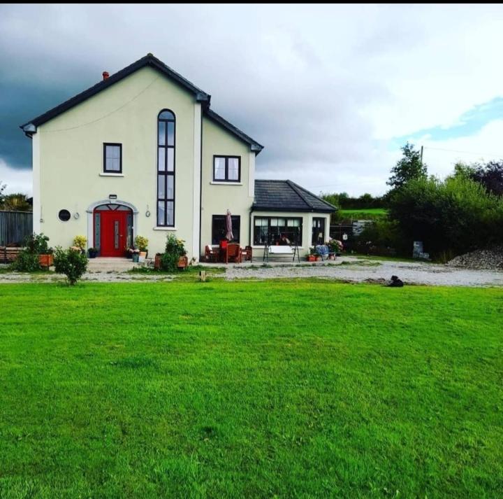 a white house with a red door in a yard at Shadowvale E34X773 in Tipperary